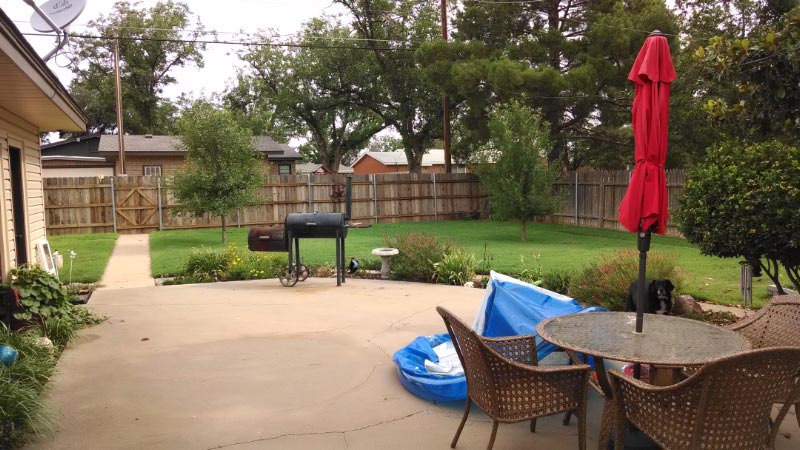 View of the fenced backyard with patio